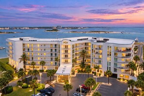 A multi-story hotel with balconies, a parking lot, and a view of the sea. - The Pass 301 | Spectacular Views of Perdido Pass | Indoor/Outdoor Pools | My Beach Getaways (Orange Beach)