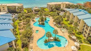 A resort with multiple buildings, a winding pool, and a beach area.
