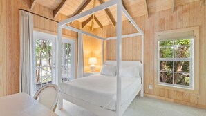 A four-poster bed in a wooden room with a large window and a table. - BRAND NEW & Waterfront 2bedroom 2bath ~ Lanai (Current)