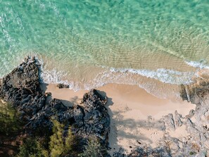 A beach with clear turquoise water, rocky formations, and sandy areas.
