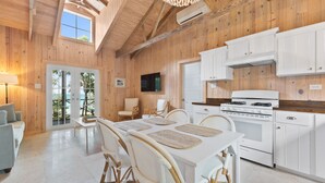 A wooden interior with a dining area, kitchen, and a large window. - BRAND NEW & Waterfront 2bedroom 2bath ~ Lanai (Current)