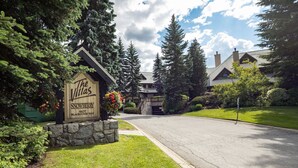 Un letrero de madera anuncia Villas Snowberry en el número 4637 de Blackcomb Way, rodeado de vegetación exuberante y un camino de entrada bien cuidado.