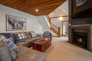 Cozy living room with a high ceiling, fireplace, and wooden coffee table.