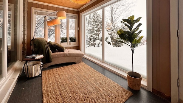 Una habitación acogedora con un amplio ventanal, techo de madera y un espacio de descanso cómodo con sofá y una mesita.
