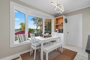 A dining area with a white table, chairs, and a view of the outdoors.