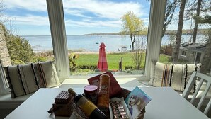 Un área de comedor con vista a un lago, una sombrilla roja y una cesta de aperitivos.