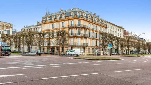 Un edificio de varios pisos con estilo arquitectónico clásico, que cuenta con balcones y grandes ventanales.