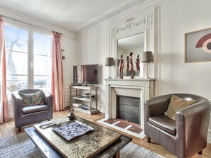 Una sala de estar con chimenea, televisor y dos sillones de cuero.