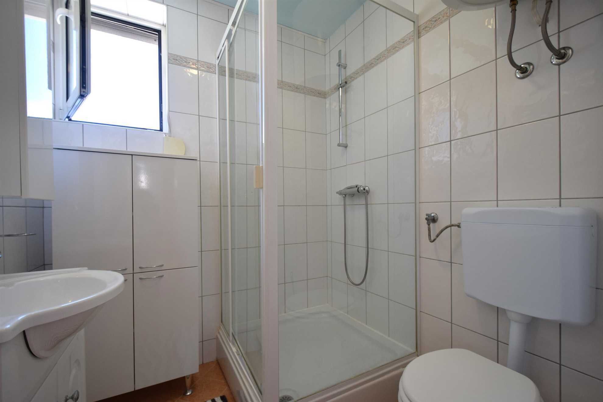 Een badkamer met douche, toilet en wastafel.