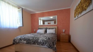 A bedroom with a bed, bedside tables, a mirror, and a window with curtains.