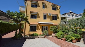 A two-story building with a yellow facade, multiple windows, and satellite dishes.