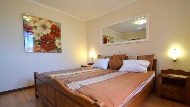 A bedroom with a wooden bed, a large mirror, and two bedside lamps. - Apartment Jelica 4 on the first floor (Njivice)