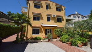 A two-story building with a yellow facade, multiple windows, and satellite dishes. - Apartment Jelica 4 on the first floor (Njivice)