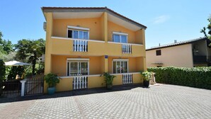 A two-story building with balconies, a paved courtyard, and potted plants. - Apartment Jelica 4 on the first floor (Njivice)