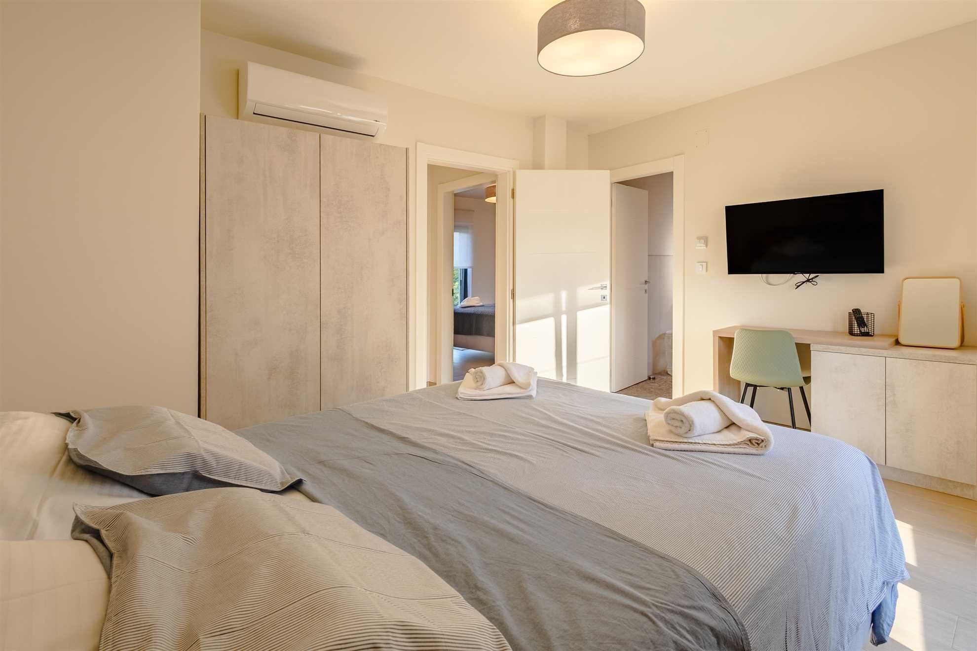 Une chambre d’hôtel équipée d’un lit, d’un bureau, d’une chaise, d’une télévision et d’un appareil de climatisation.