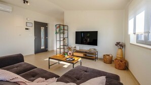 Un salon moderne comprenant un canapé, une table basse, un téléviseur et des objets décoratifs.