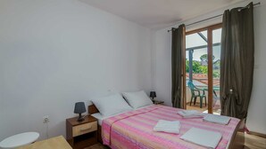 A bedroom with a bed, bedside tables, a nightstand, a window with curtains, and a view of the outside. - Apartment Katja 3 with sea view (Njivice)