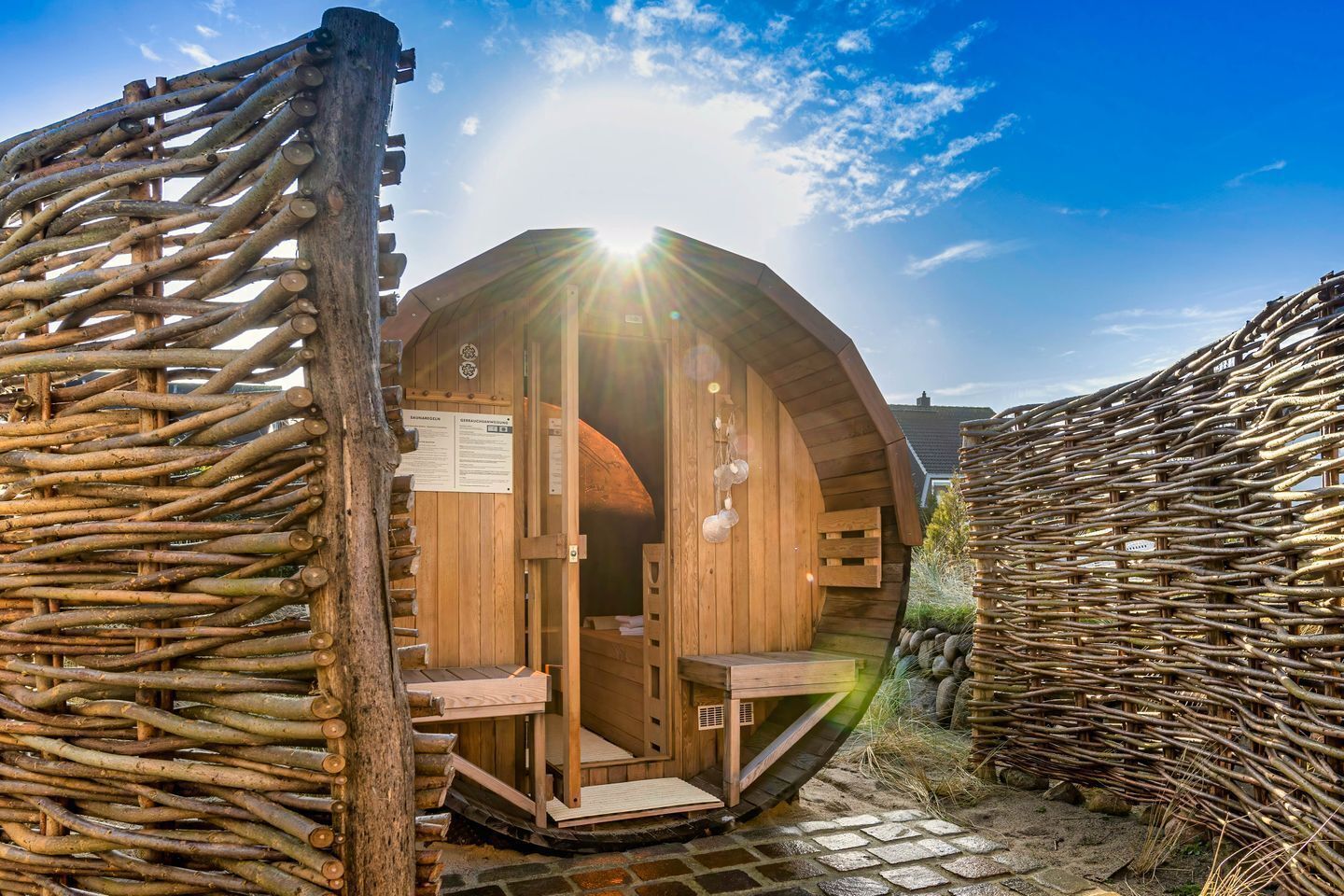 A wooden sauna structure with a curved roof, a wooden entrance, and a small seating area inside.