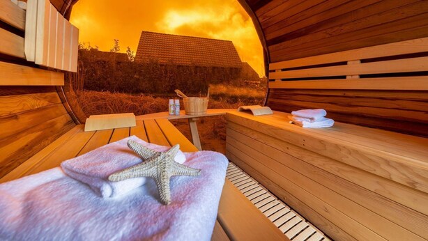 Een sauna met houten banken, een handdoek in de vorm van een zeester, een emmer en flessen.