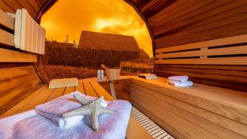 A sauna with wooden benches, a starfish towel, a bucket, and bottles.