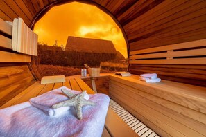 A sauna with wooden benches, a starfish towel, a bucket, and bottles. - Westerländer Perle House - Where Sylt Shows Its Most Beautiful Side (Sylt)