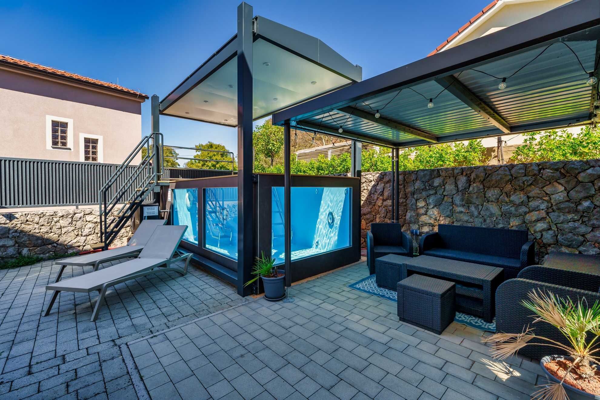 A patio area with a hot tub, outdoor seating, and a covered area.