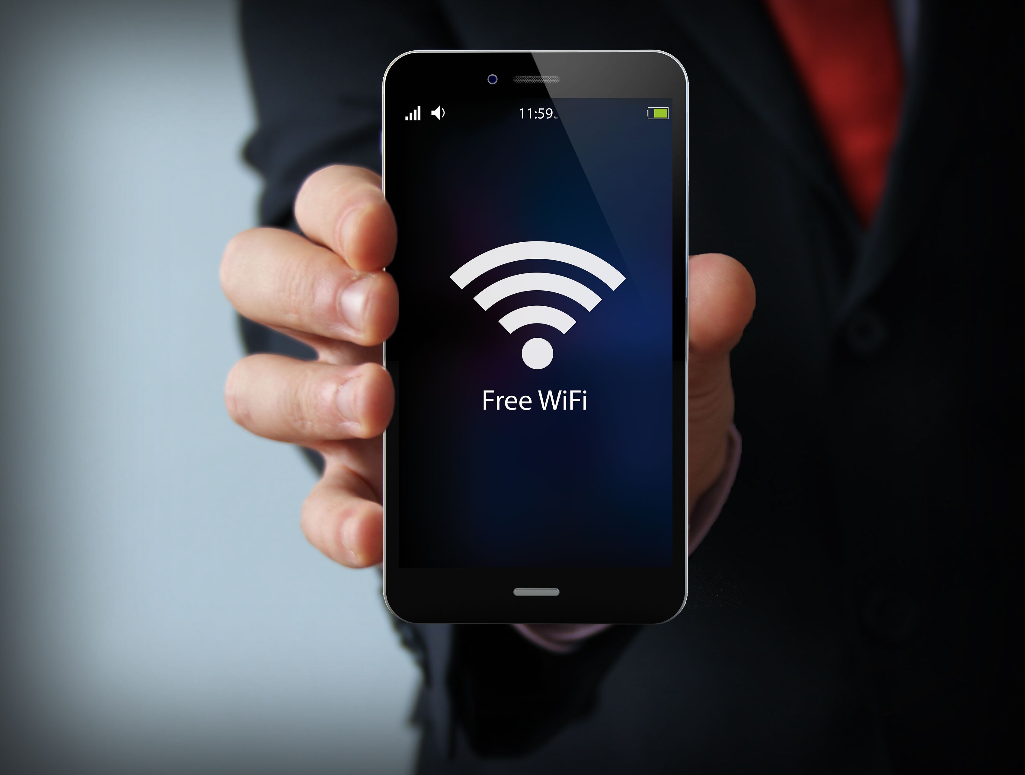 A person holding a smartphone displaying a WiFi icon with the text "Free WiFi".