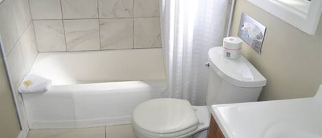 Un baño con bañera, inodoro y lavamanos.