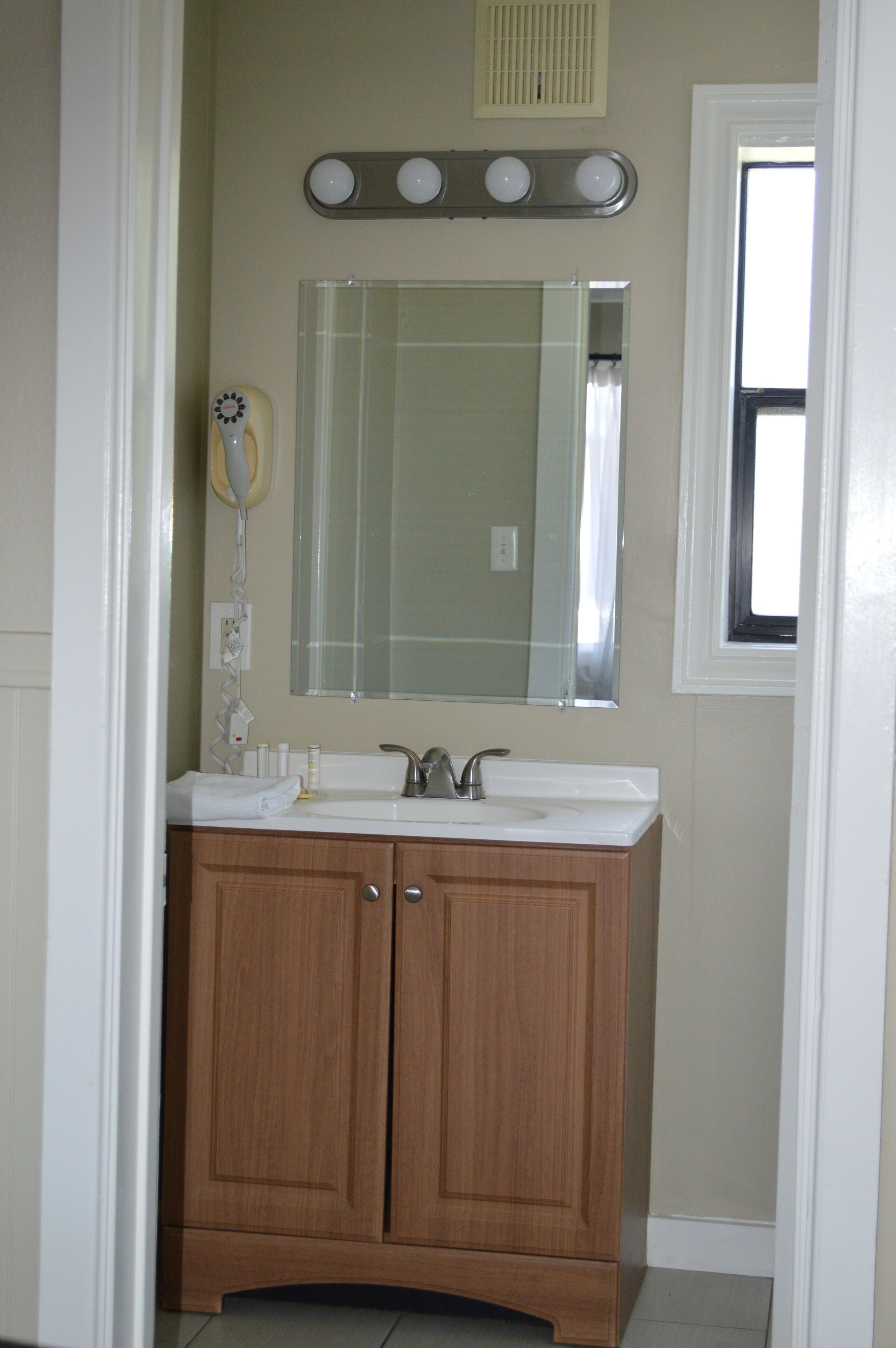 Un baño con tocador de madera, un espejo y una lámpara sobre el lavabo.