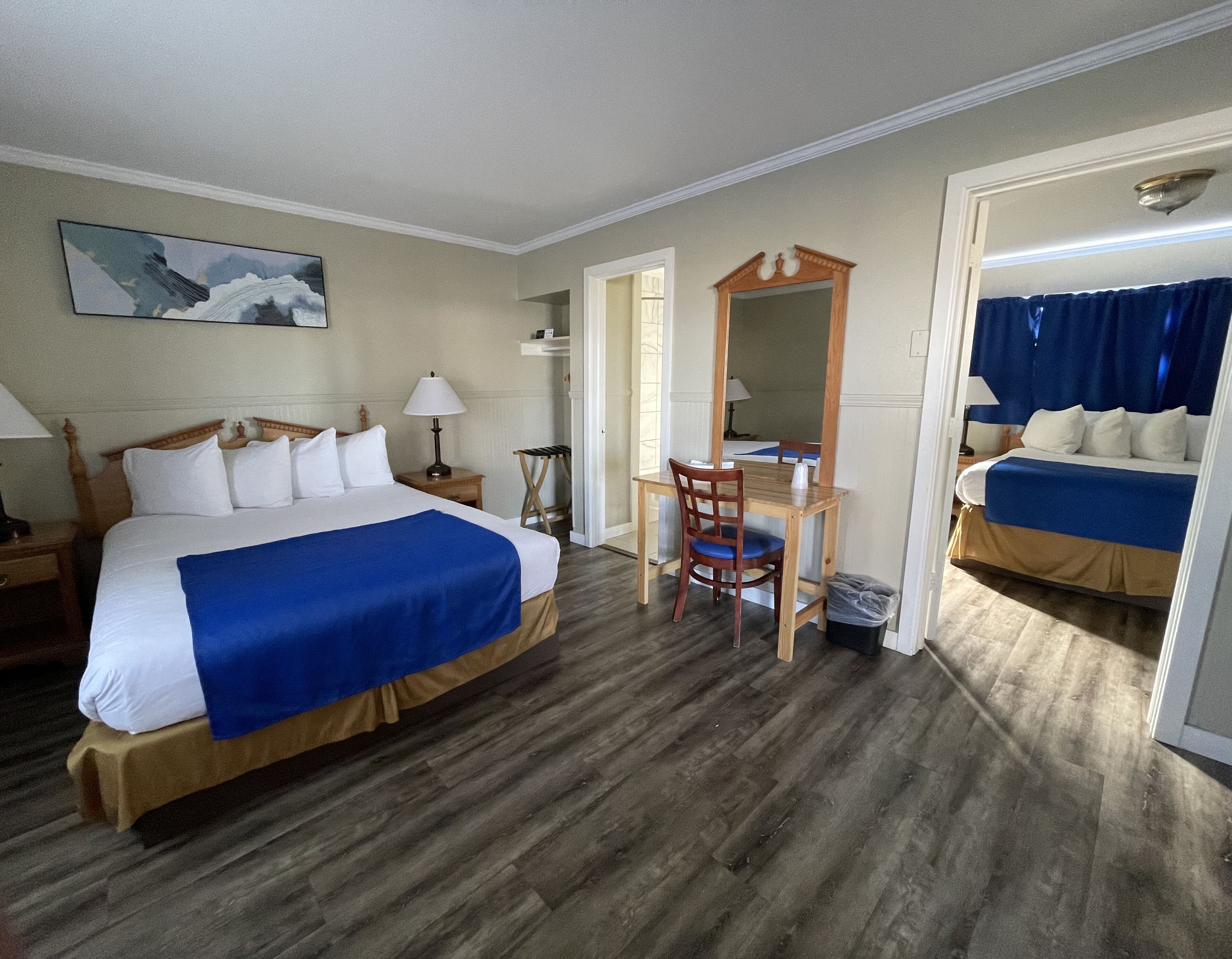 Een hotelkamer met een bed, bureau, stoel en een grote spiegel.