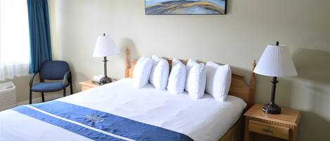 A hotel room with a large bed, two bedside tables with lamps, a chair, and a painting on the wall.