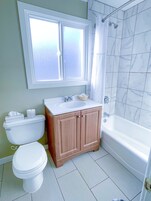 A bathroom with a toilet, sink, vanity, and bathtub.