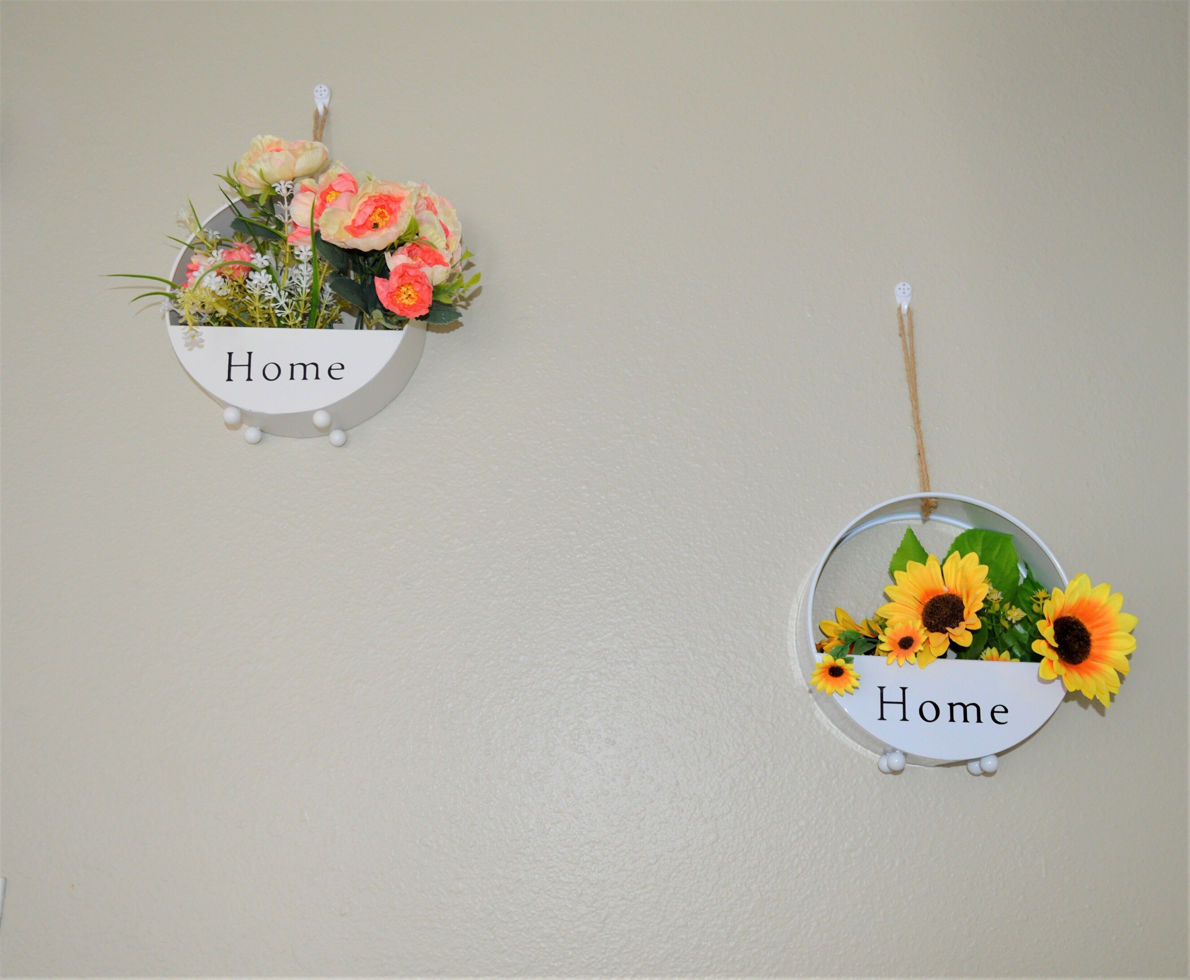 Dos letreros montados en la pared con la palabra 'Home' y adornos florales.