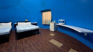 Une chambre avec deux lits, un bureau, un ventilateur de plafond et une fenêtre avec des rideaux.