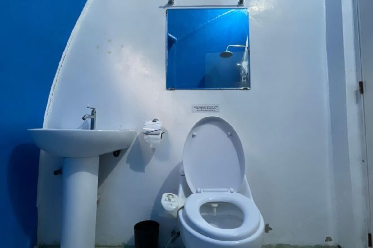 Une petite salle de bain avec des toilettes blanches, un lavabo et une petite fenêtre.