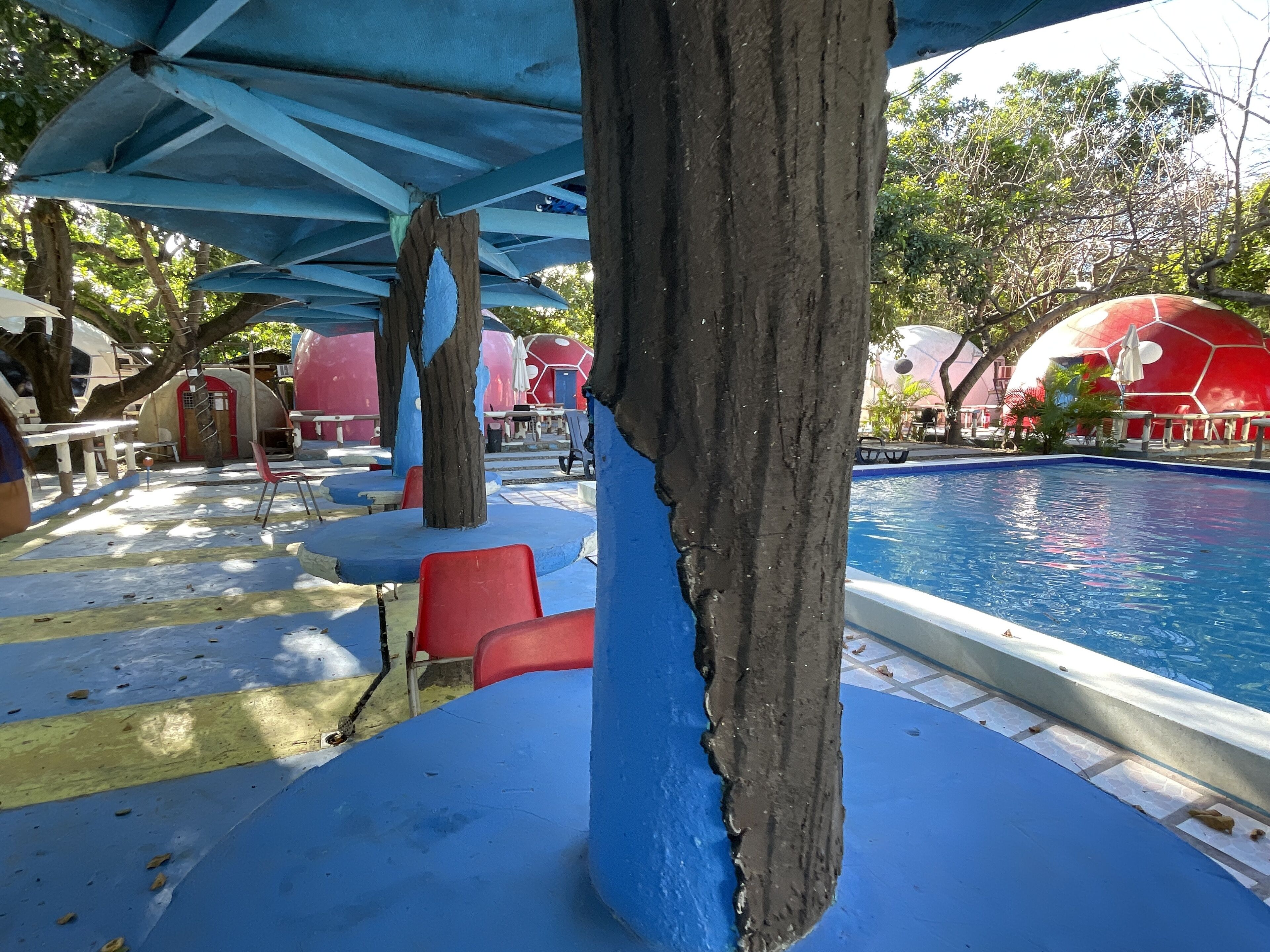 A pool area with a blue and red color scheme, including a large tree trunk and a red dome-shaped structure.