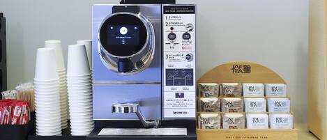 A Nespresso coffee machine with instructions, disposable cups, and a display of tea bags.