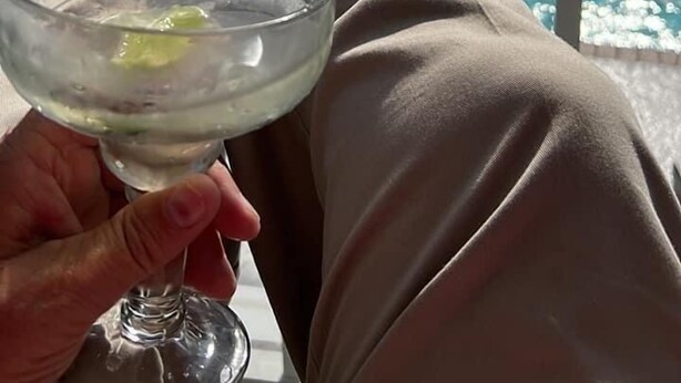 A person relaxing by a pool with a drink in hand. - The Bays Edge Retreat Waterfront (Bradenton)