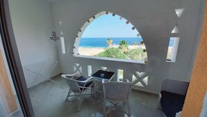 A balcony with two wicker chairs, a small table, and a view of the beach and ocean. - Domina Coral Bay Sultan - Private room (Sharm el Sheikh)