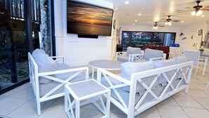 A modern interior with white furniture, a large TV displaying a sunset, and a view of the outdoors. - C14 Moon Bay - Recently renovated 2 bedroom townhome (Key Largo)
