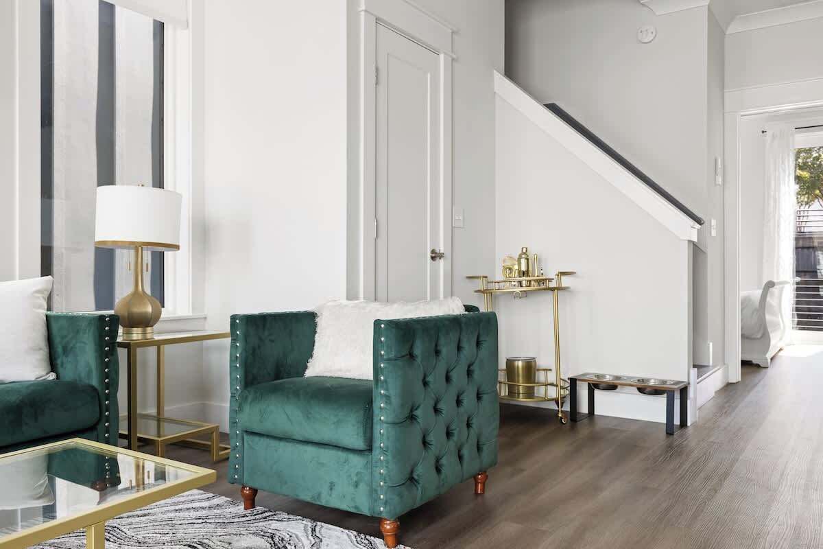 A living room with a green armchair, a glass coffee table, and a lamp.