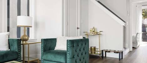 A living room with a green armchair, a glass coffee table, and a lamp.