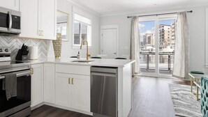 A modern kitchen with white cabinetry, a built-in oven, and a dishwasher. - Inspiration at The Cove Riverwalk Villas (Wilmington)