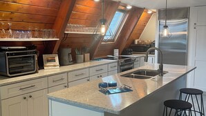 Uma cozinha moderna com ilha central, banquetas e claraboia.