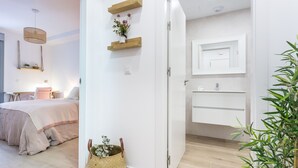 Une chambre moderne avec un lit, une table de chevet et une étagère murale agrémentée d’une plante.