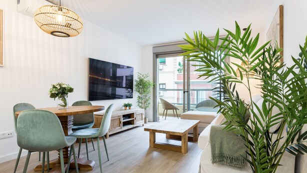 Un salon moderne comprenant un coin repas, un grand téléviseur et un balcon avec vue.