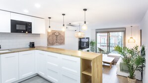 Une cuisine moderne avec des meubles blancs, un îlot central en bois et des luminaires suspendus.