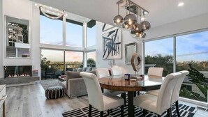 A modern dining area with a round table, white chairs, and a chandelier.