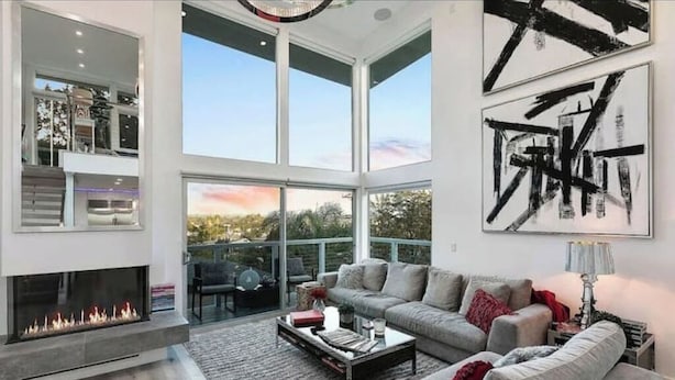 A spacious living room with a fireplace, a large window, and abstract art on the wall.