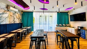 A restaurant with wooden tables and chairs, a marble wall, teal curtains, and pendant lighting. - Lighthouse Point Hotel (Dumaguete)